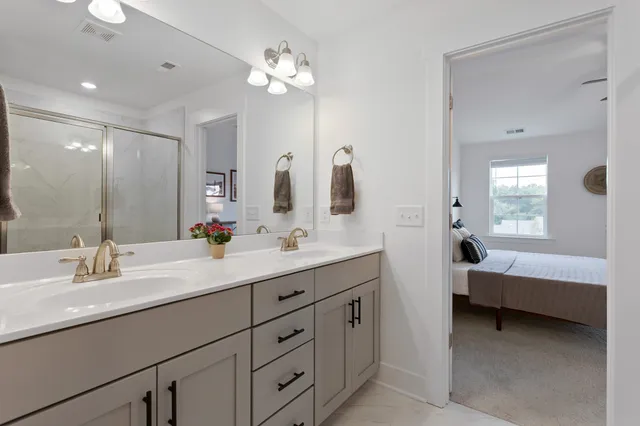 a en suite bathroom with double vanity a sink and a mirror