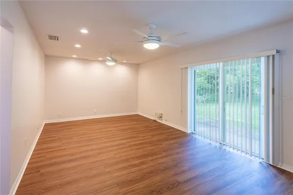 a view of empty room with wooden floor and fan