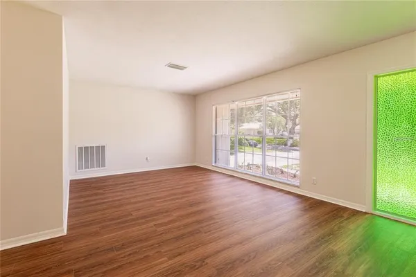a view of an empty room with wooden floor and a window