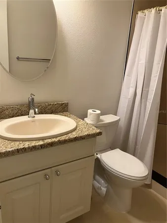 a bathroom with a granite countertop toilet sink and mirror