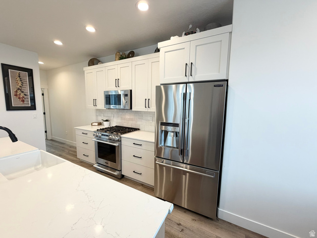 545 East 7215 South Midvale, UT 84047 - Photo 5 of 27 Kitchen with stainless steel appliances, light wood finished floors, white cabinets, recessed lighting, and light stone counters
