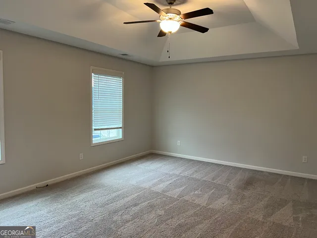 an empty room with windows and fan