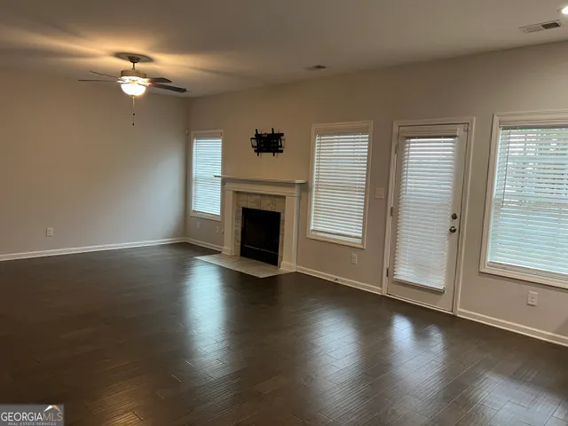 an empty room with wooden floor fireplace and windows
