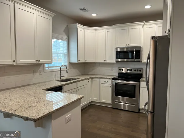 a kitchen with stainless steel appliances granite countertop a sink stove and refrigerator