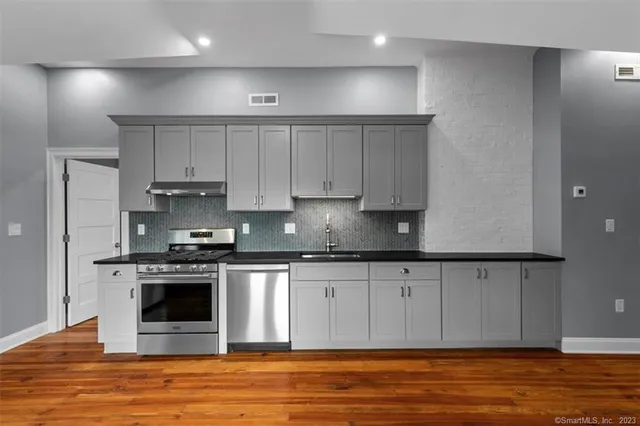 a kitchen with stainless steel appliances granite countertop a stove a sink and a refrigerator