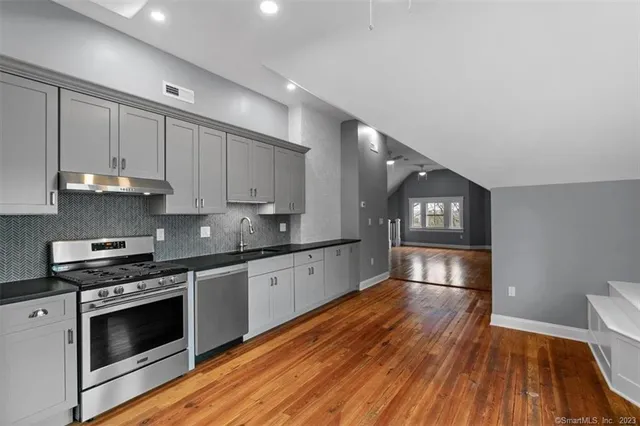 a kitchen with granite countertop wooden floors appliances and cabinets