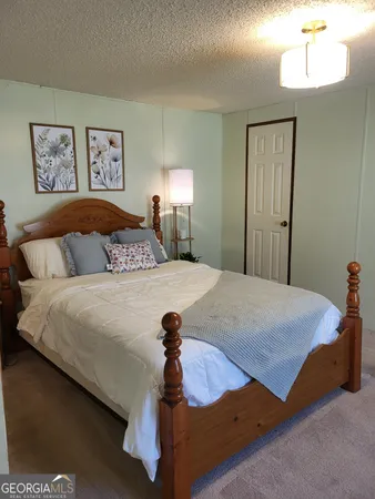 a spacious bedroom with a bed and a lamp