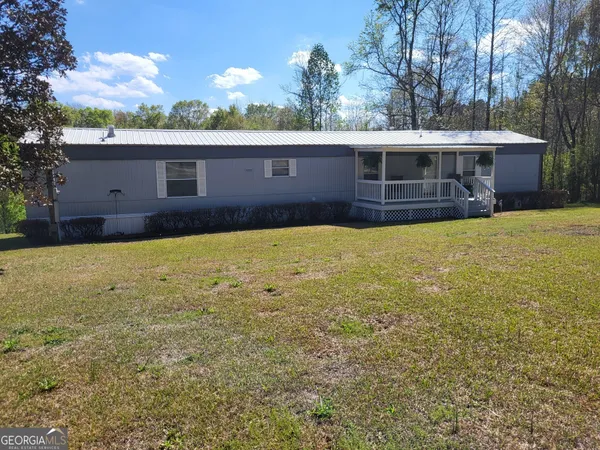 a view of house with yard and a tree
