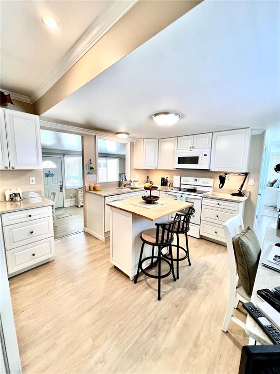 72 4th Avenue, Unit 72 Venice, FL 34285 - Photo 5 of 29 a kitchen with a refrigerator a stove top oven a sink dishwasher and white cabinets with wooden floor