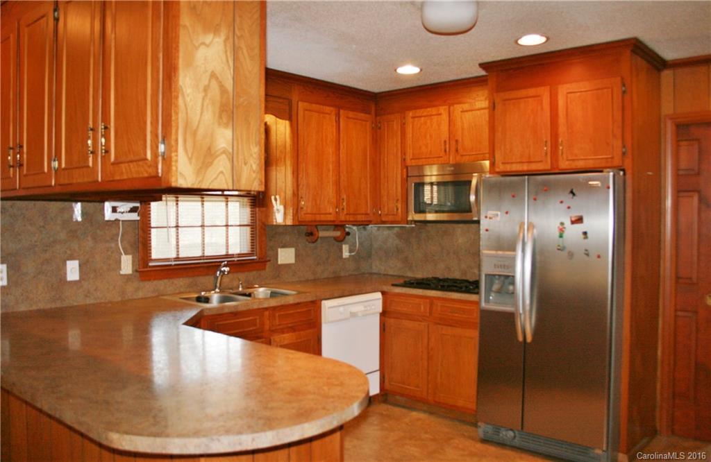 2512 Old Camden Road Monroe, NC 28110 - Photo 14 of 23 a kitchen with stainless steel appliances granite countertop a sink a refrigerator and wooden cabinets