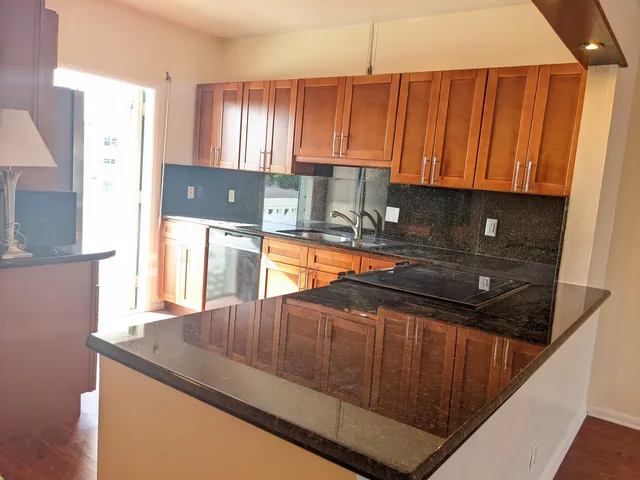 a kitchen with granite countertop a sink a stove and a microwave oven in a cabinets