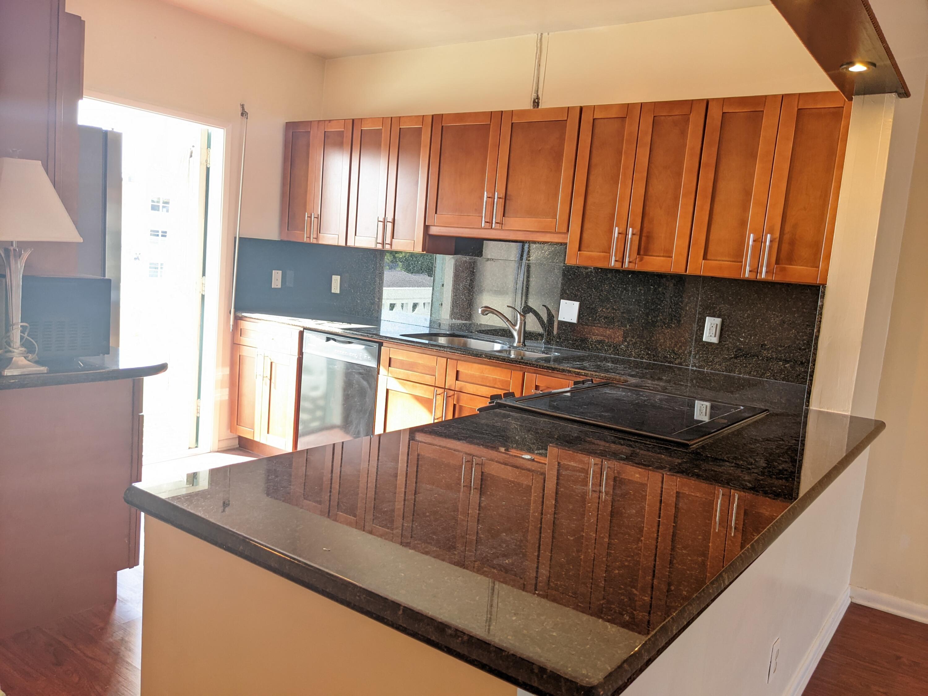 2772 Northeast 30th Avenue, Unit 6C Lighthouse Point, FL 33064 - Photo 13 of 16 a kitchen with granite countertop a sink a stove and a microwave oven in a cabinets