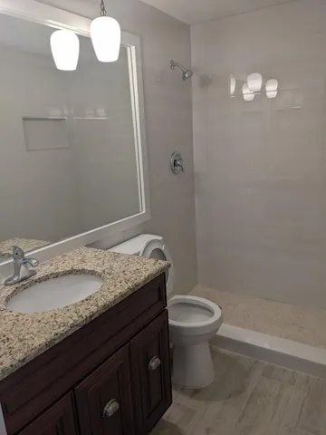 a bathroom with a granite countertop sink toilet and a mirror