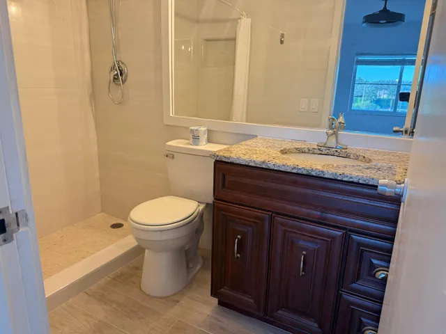 a bathroom with a granite countertop sink toilet and shower