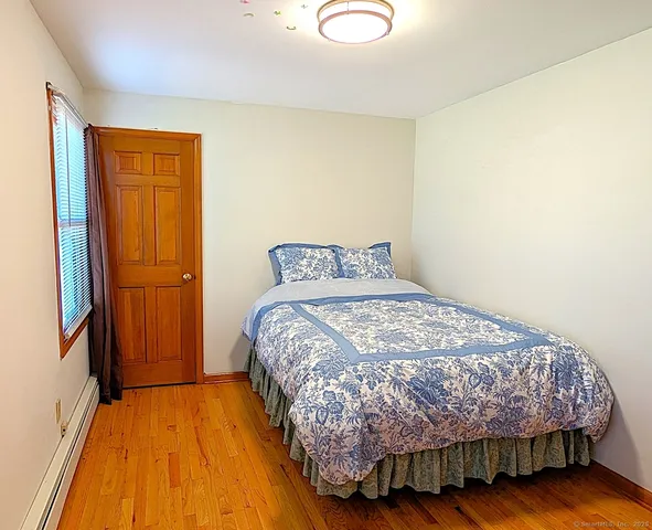 a bedroom with bed and wooden floor