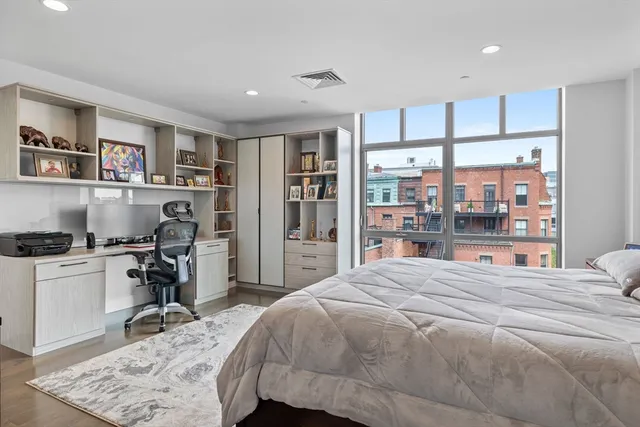 a bedroom with a bed a table and a large window