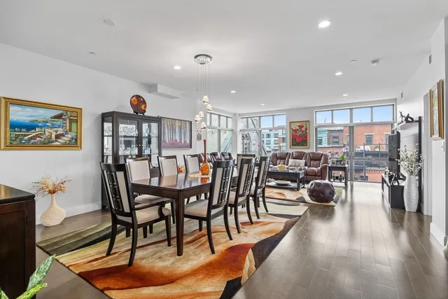 a view of a dining room and livingroom with furniture wooden floor a rug a painting and a chandelier