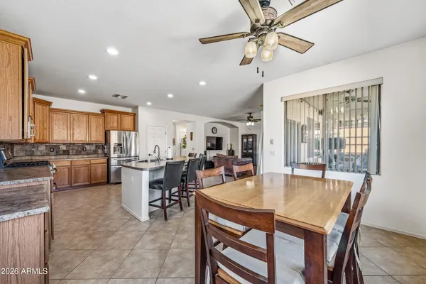 a dining room with stainless steel appliances kitchen island granite countertop a dining table chairs and a refrigerator