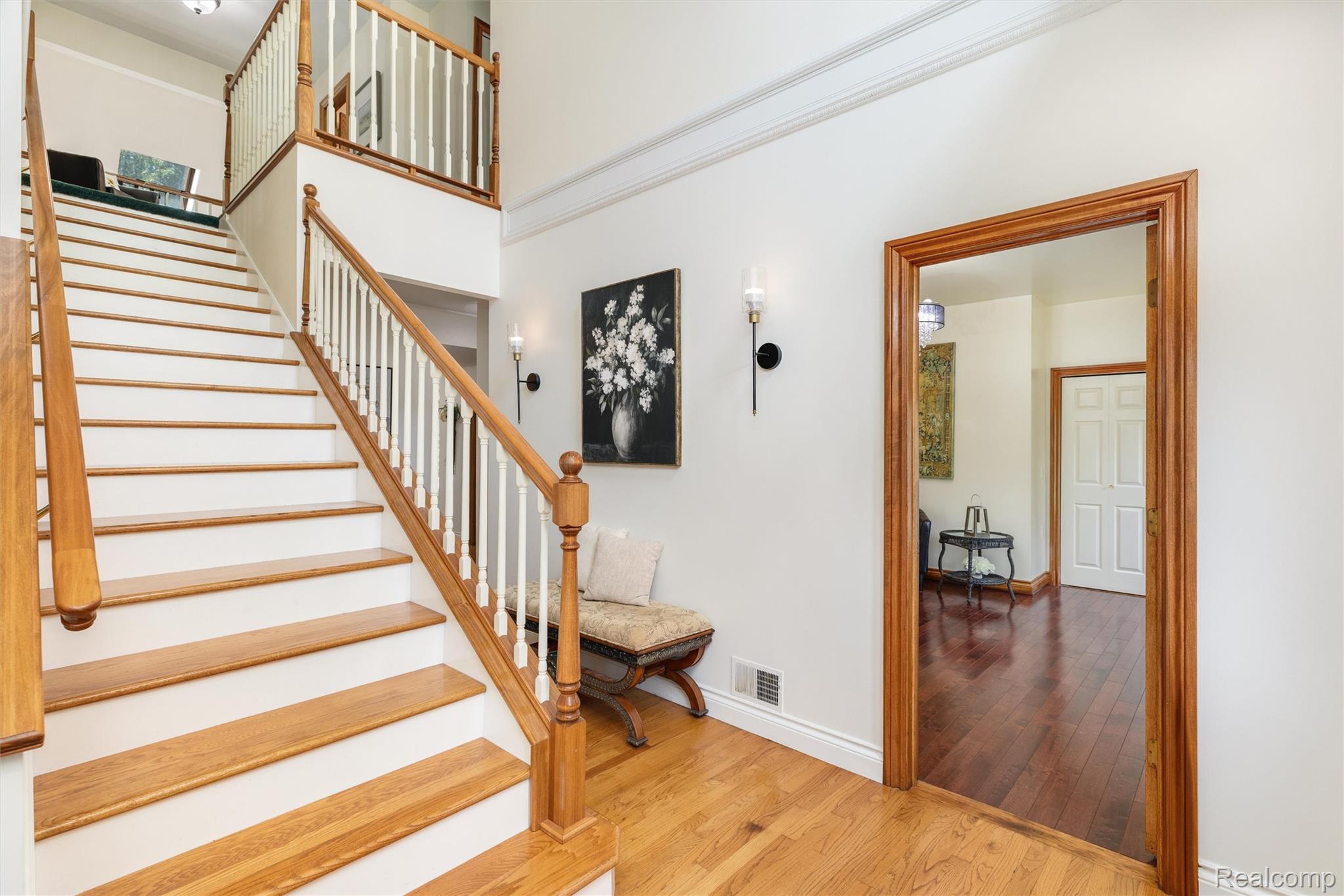 21280 Merriman Road New Boston, MI 48164 - Photo 7 of 65 Hardwood flooring, wood staircase with white risers, wood newel posts, and recessed wall sconces
