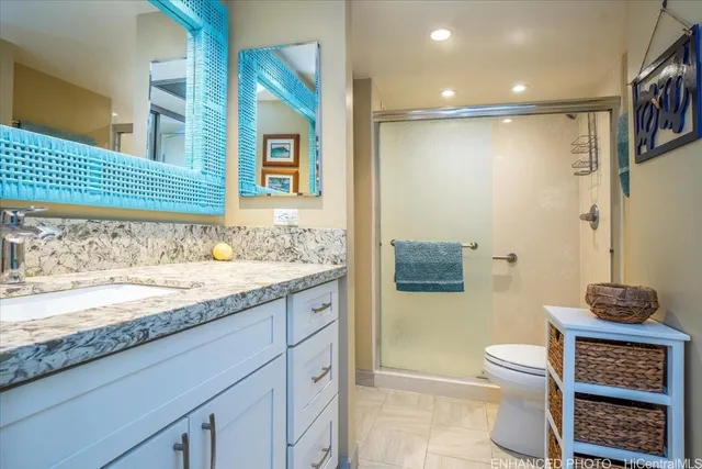 a bathroom with a granite countertop sink a toilet and a shower