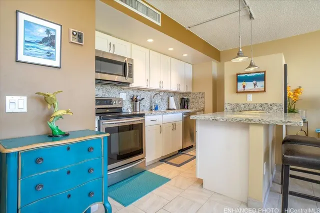 a kitchen with stainless steel appliances kitchen island granite countertop a refrigerator a stove a sink dishwasher and white cabinets with wooden floor