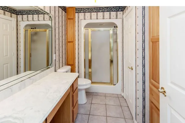 a bathroom with a granite countertop sink a toilet and a mirror