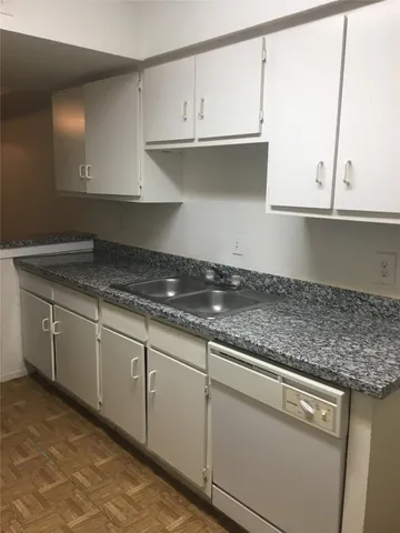 a kitchen with granite countertop a sink stove and cabinets