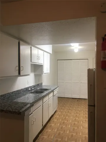 a kitchen with granite countertop a stove and a white cabinets