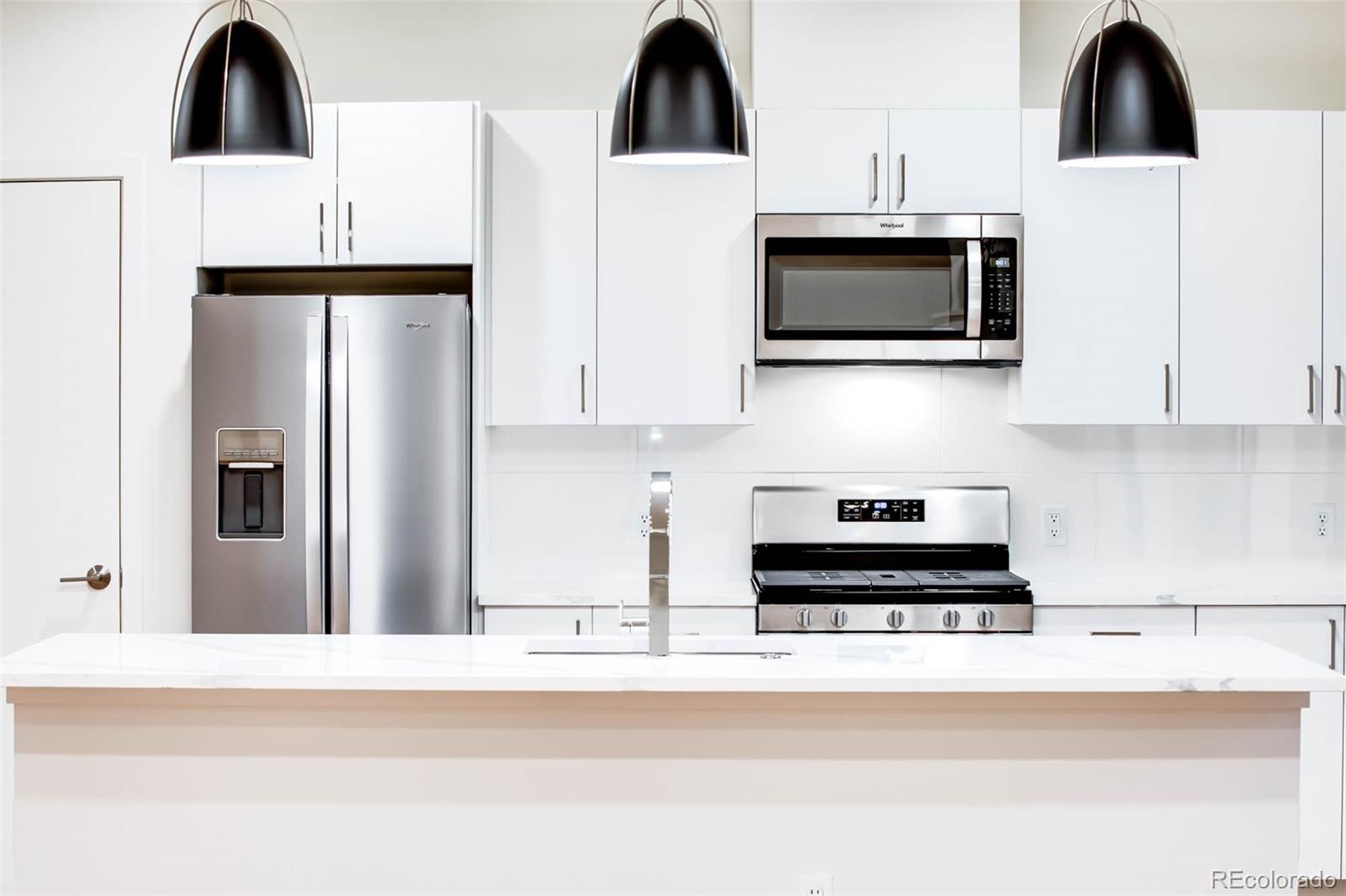 a kitchen with stainless steel appliances a stove a microwave a sink and white cabinets