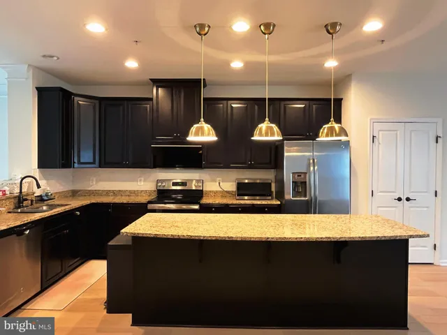 a kitchen with stainless steel appliances a sink dishwasher a stove and a refrigerator with wooden floor