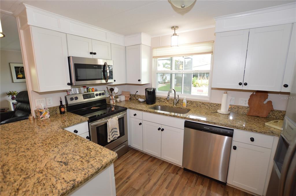 140 Rarotonga Road North Port, FL 34287 - Photo 8 of 42 a kitchen with kitchen island granite countertop a sink appliances cabinets and a counter top space