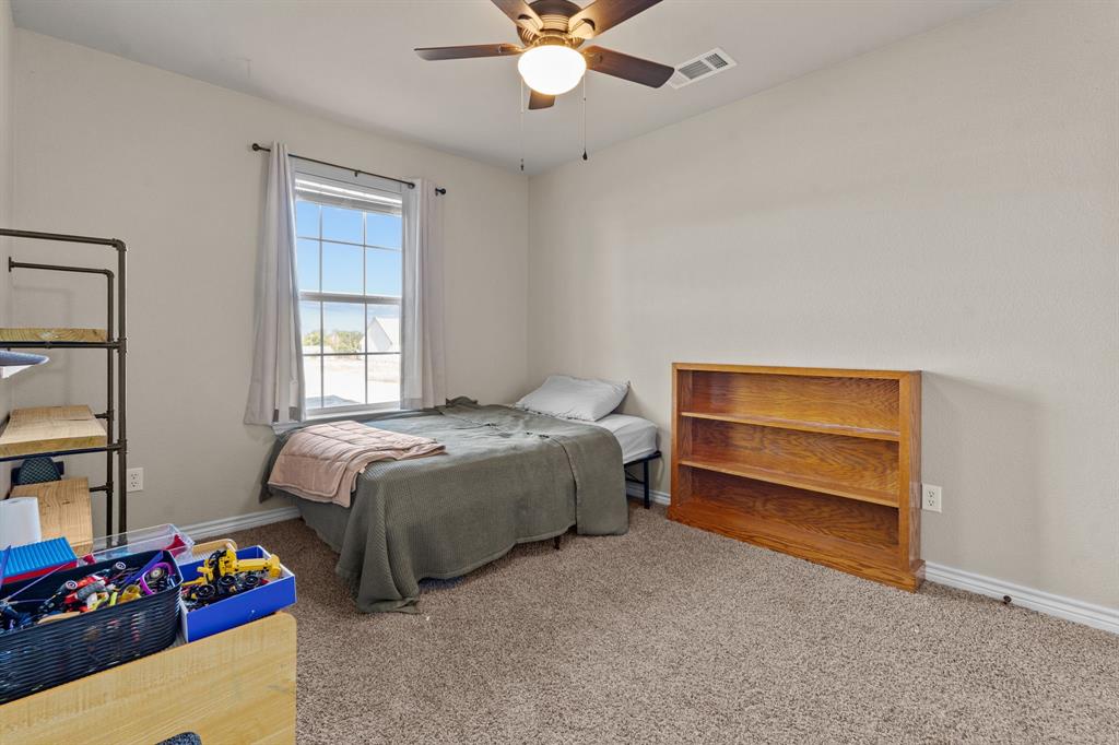 509 Pecan Tree Court Poolville, TX 76487 - Photo 15 of 25 a bedroom with a bed and a chandelier