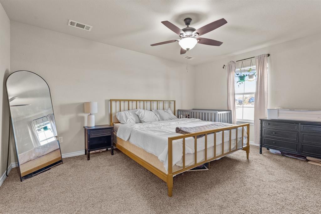 509 Pecan Tree Court Poolville, TX 76487 - Photo 16 of 25 a bedroom with a bed a chandelier and dresser