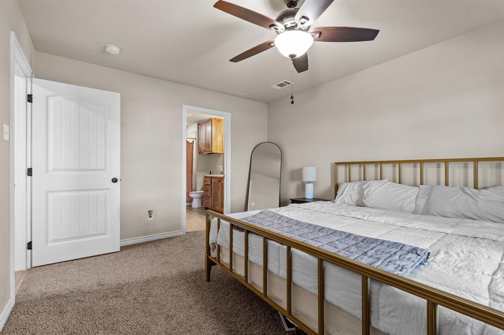509 Pecan Tree Court Poolville, TX 76487 - Photo 17 of 25 a bedroom with a large bed and a chandelier