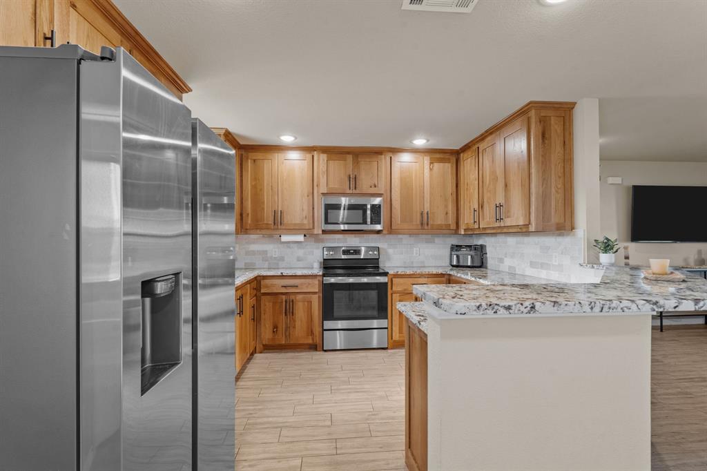 509 Pecan Tree Court Poolville, TX 76487 - Photo 7 of 25 a kitchen with stainless steel appliances granite countertop a refrigerator a stove top oven a sink and dishwasher