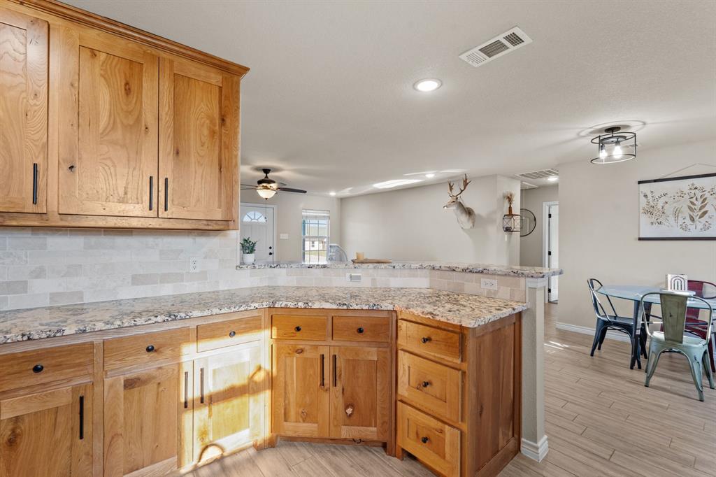 509 Pecan Tree Court Poolville, TX 76487 - Photo 8 of 25 a kitchen with granite countertop a sink cabinets and wooden floor