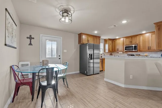 a kitchen with stainless steel appliances kitchen island granite countertop a refrigerator a stove a microwave oven with a dining table and chairs