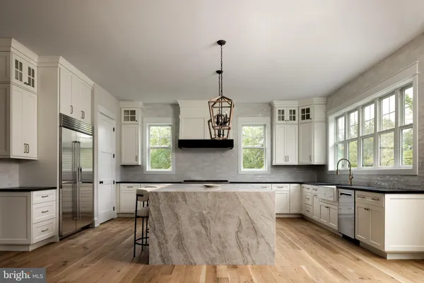 a kitchen with granite countertop a refrigerator a stove a sink and white cabinets with wooden floor