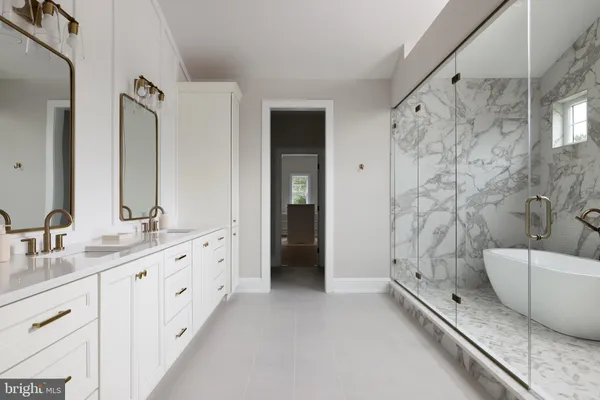 a en suite bathroom with a double vanity sink a large mirror and a bathtub