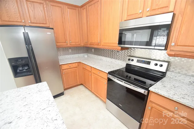 a kitchen with granite countertop a refrigerator stove and sink