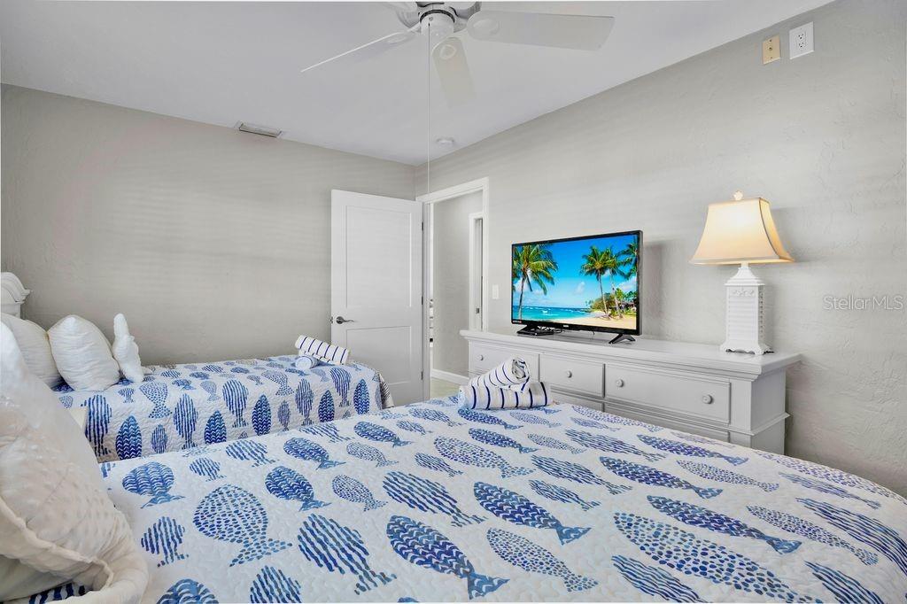 5830 Midnight Pass Road, Unit 107 Sarasota, FL 34242 - Photo 16 of 18 a bedroom with a bed and a flat screen tv