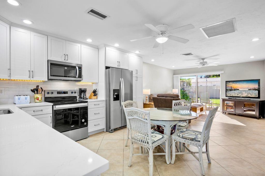 5830 Midnight Pass Road, Unit 107 Sarasota, FL 34242 - Photo 3 of 18 a kitchen with refrigerator a stove and chairs