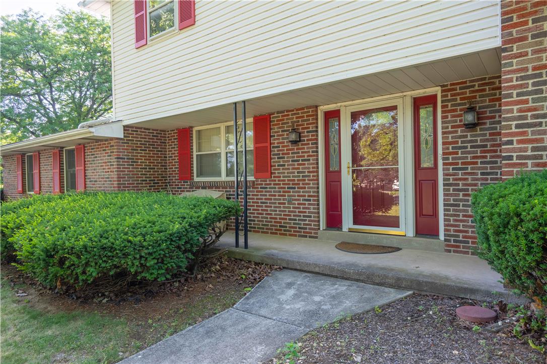 5425 Clauser Road Orefield, PA 18069 - Photo 5 of 18 A classic brick and siding residence, featuring a welcoming red front door and vibrant red shutters, nestled within mature landscaping.