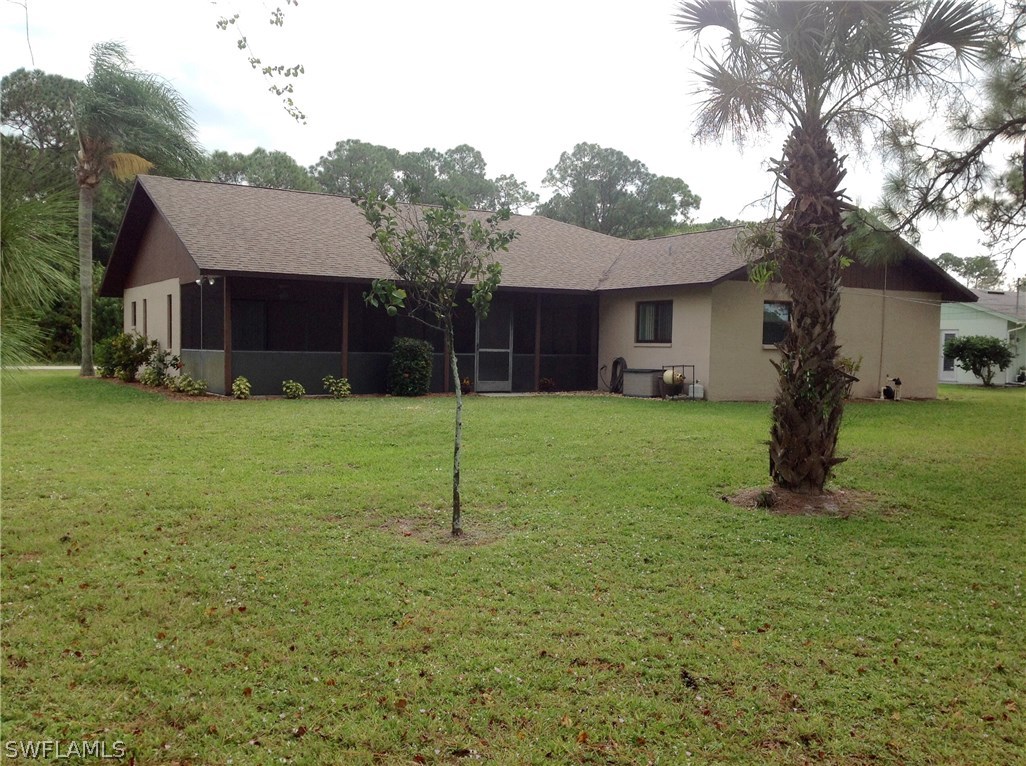 25 Michigan Road Lehigh Acres, FL 33936 - Photo 3 of 16 a house that is sitting in the grass with large trees
