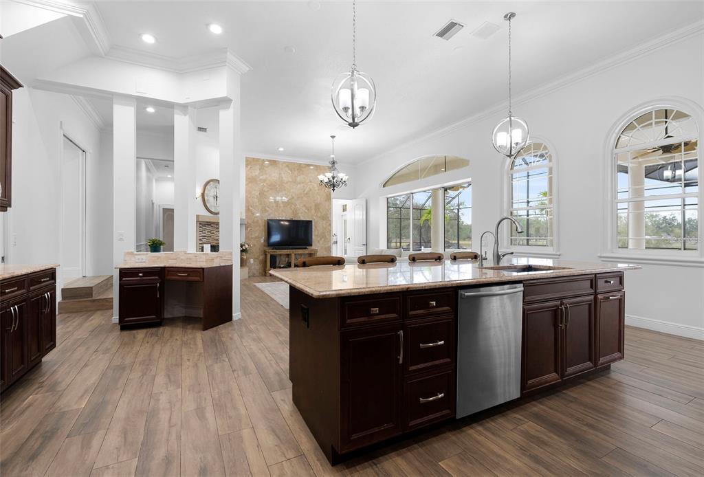 1450 Bern Creek Loop Sarasota, FL 34240 - Photo 25 of 95 a large kitchen with stainless steel appliances granite countertop a stove a sink dishwasher a living room with wooden floor and cabinets