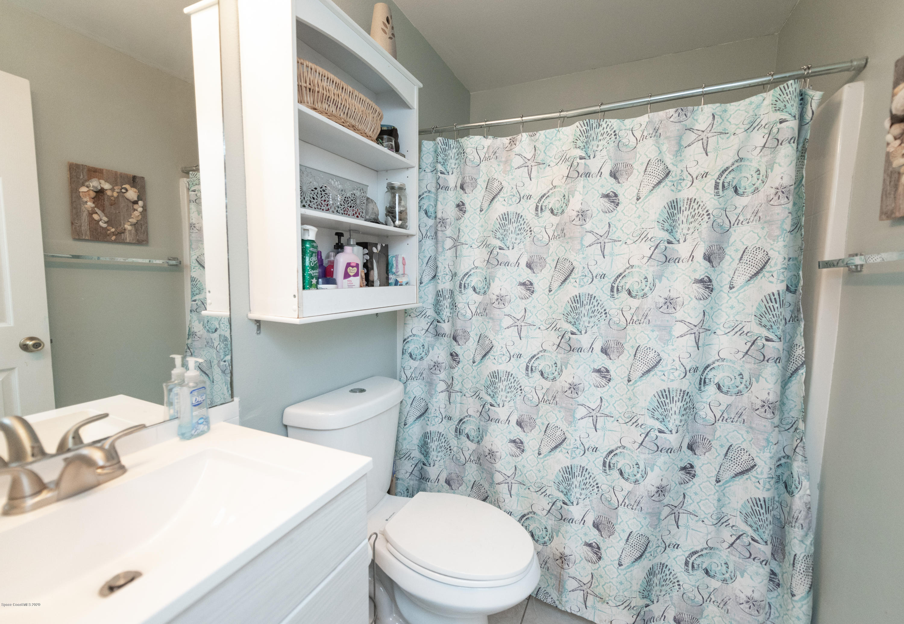 6040 Adina Road Cocoa, FL 32927 - Photo 14 of 23 a bathroom with a sink a toilet and a shower curtain