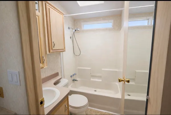 a bathroom with a granite countertop bathtub shower sink vanity and toilet