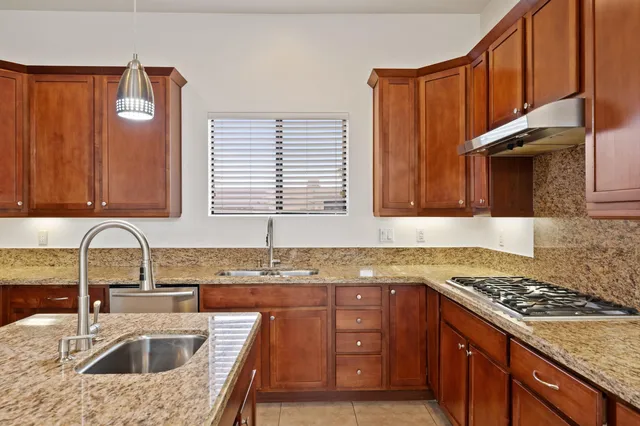 a kitchen with stainless steel appliances granite countertop wooden cabinets a sink and a stove