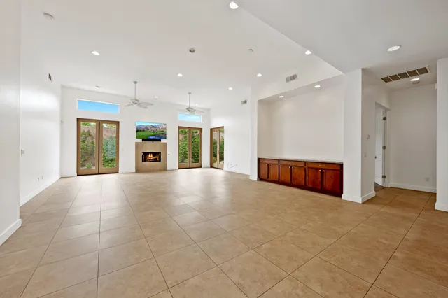 a view of an empty room with a window and kitchen view