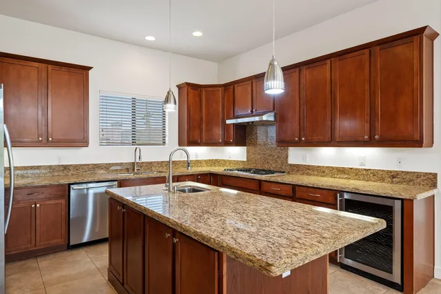 a kitchen with stainless steel appliances granite countertop a sink a center island and windows